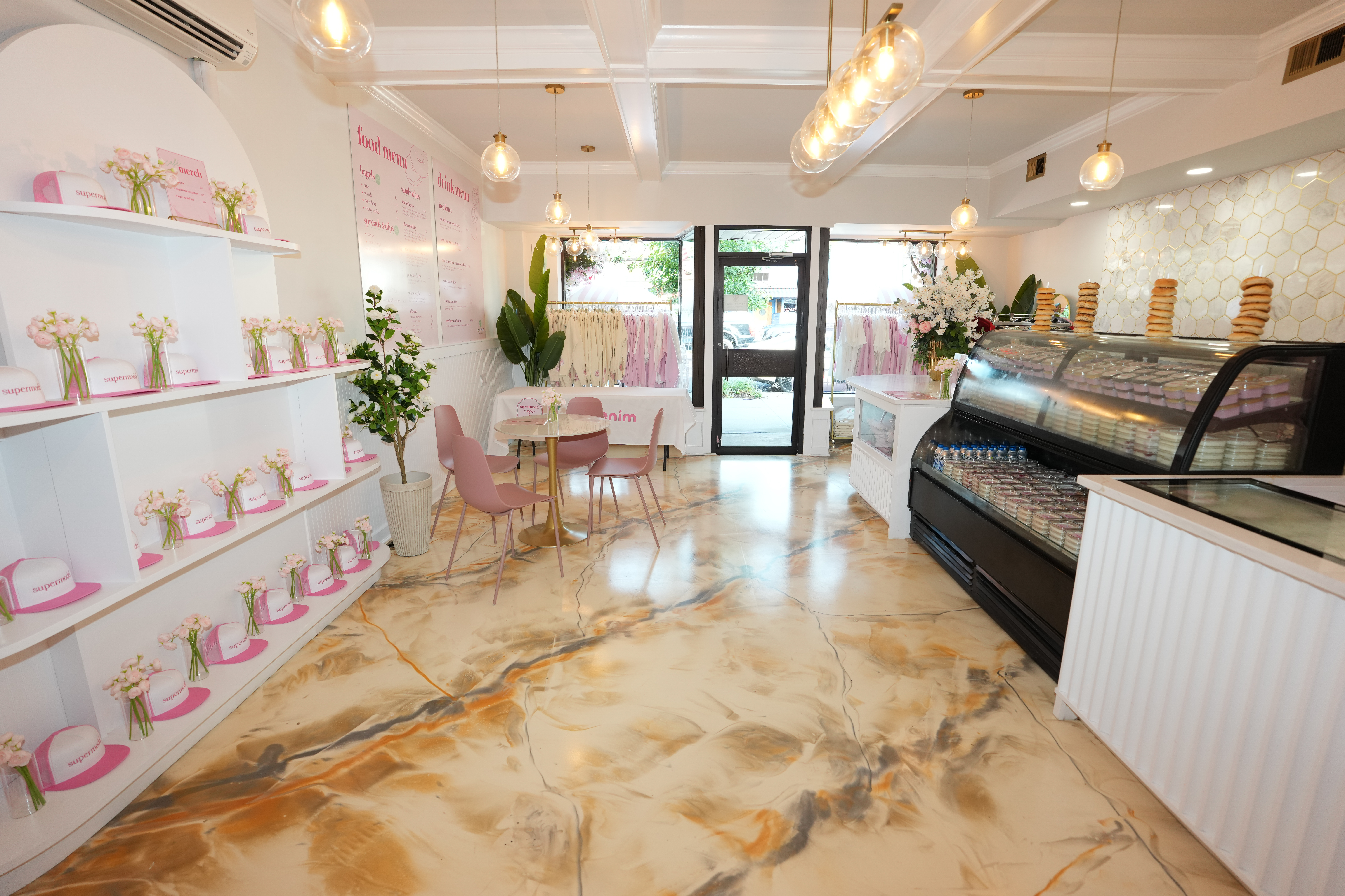 Interior of the Supermodel Cafe, showing a dining area, merchandise, and a display case with food items.